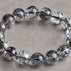 Vòng đá thạch anh tóc đen (Black Rutilated Quartz) là vật phẩm phong thủy quyền năng, mang năng lượng dương mạnh mẽ giúp xua đuổi tà khí và thu hút may mắn. Với các sợi bao thể Tourmaline đen huyền bí ẩn mình trong lòng đá trong suốt, đây là sự lựa chọn hàng đầu cho phụ nữ hiện đại cần sự tự tin và quyết đoán.